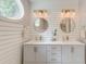 Bright bathroom featuring a white double vanity, round mirrors, oval window and shiplap walls at 128 Paul Dr, Summerville, SC 29483