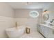 Bright and modern bathroom featuring a freestanding tub, oval window, white vanity, and shiplap walls at 128 Paul Dr, Summerville, SC 29483