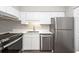 Modern kitchen features stainless steel appliances, white cabinetry, and countertops, with a stainless steel double sink at 142 Marsh View Villas, Folly Beach, SC 29439