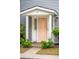 A peach-colored front door with white trim and plants surrounding the entrance of the townhouse at 153 Heritage Cir # K3, Mount Pleasant, SC 29464