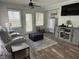 Cozy living room with hardwood floors, gray sofa and ottoman, ceiling fan, and flat screen TV at 1606 Waterside Blvd, Moncks Corner, SC 29461