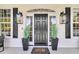 Elegant front entrance featuring a black door flanked by stylish lanterns and lush greenery at 1711 Indigo Island Dr, Hanahan, SC 29410