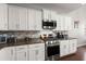 Close-up of kitchen with stainless steel appliances, white cabinetry and dark granite countertops at 203 Yeamans Way, Summerville, SC 29483
