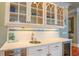 Elegant bar area with marble countertop, white cabinetry, glass shelves, and stainless steel beverage center at 25 Ocean Point Dr, Isle of Palms, SC 29451