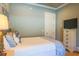 Bedroom with white dresser, white walls, TV, and black metal framed bed with blue and white pillows at 25 Ocean Point Dr, Isle of Palms, SC 29451