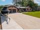 Expansive driveway leading to a brick home with a two-car garage and lush green lawn at 2864 Wofford Rd, Charleston, SC 29414