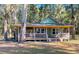 Charming exterior of a green cottage-style home surrounded by mature trees at 3360 Baldwin Ln, Green Pond, SC 29446