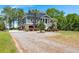 Charming raised beach house with brick facade, mature landscaping, and crushed gravel driveway at 423 Lake Moultrie Dr, Bonneau, SC 29431