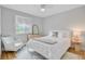 Cozy bedroom featuring a white bed, chair, and neutral tones, enhanced by natural light and a patterned area rug at 5 Mariners Cay Dr, Folly Beach, SC 29439