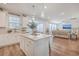 Modern kitchen with white cabinets, stainless steel appliances, central island and hardwood floors leading to living room at 612 S Pointe Blvd, Summerville, SC 29483