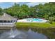 Aerial view of a community pool with picnic tables and a nearby pond with fountain at 7955 Timbercreek Ln # 1807, North Charleston, SC 29418