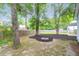Landscaped backyard featuring a fire pit, mature trees, mulch, and a wooden fence at 8451 Walsham St, North Charleston, SC 29420