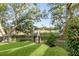 Backyard with lush green lawn, garden, and a view of a dock leading into the marsh, set behind mature trees at 853 Whispering Marsh Dr, Charleston, SC 29412