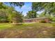 Lush backyard with mature trees, a spacious lawn, and a brick house in a serene setting at 106 Newington Rd, Summerville, SC 29485