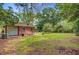 View of the backyard and detached garage with a big lawn surrounded by mature trees at 106 Newington Rd, Summerville, SC 29485