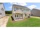 Back exterior view of a tan two-story home with a screened in porch and large backyard at 120 Shingle Oak Dr, Moncks Corner, SC 29461
