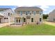 Back exterior view of a tan two-story home with a screened in porch and spacious green backyard at 120 Shingle Oak Dr, Moncks Corner, SC 29461