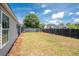 Wide view of the backyard showing the house exterior, fence, lawn, and mature trees at 1315 Palm Cove Dr, Charleston, SC 29492