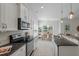 Galley style kitchen with granite countertops and stainless steel appliances overlooking the dining area at 1610 Fishbone Dr, Johns Island, SC 29455