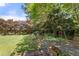 Lush backyard with mature trees, manicured lawn, and a stone pathway leading to a cozy seating area at 1708 Waterbrook Dr, Charleston, SC 29414