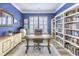 Elegant office with blue walls, custom built-in bookshelves, a wooden desk, and ample natural light from shuttered windows at 172 Helena Park Dr, Summerville, SC 29486