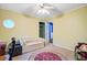 A bedroom features yellow walls, a ceiling fan, a window, and a small cream-colored sofa at 1830 Kempton Ave, James Island, SC 29412