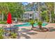 Community pool area with lounge chairs, tables with red umbrellas, lush landscaping, and trees at 188 Midland Pkwy # 516, Summerville, SC 29485