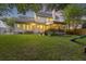 Expansive backyard featuring a screened porch, lush lawn and mature trees at twilight at 1901 Bairds Cv, Charleston, SC 29414