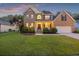 Charming brick two-story home with a well-manicured lawn and attached two-car garage at sunset at 1901 Bairds Cv, Charleston, SC 29414