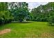 Lush green backyard with mature trees and space for outdoor activities with a view of the house in the distance at 1976 Liberia Rd, Wadmalaw Island, SC 29487