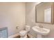 A well-lit powder room with wood floors, toilet, pedestal sink, and decorative mirror at 212 Palmetto Walk Dr, Summerville, SC 29486