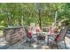 Well-equipped outdoor kitchen featuring a stone counter, grill, sink, and seating area surrounded by lush trees at 25 Fitzroy Dr, Charleston, SC 29414