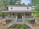 Charming two-story home with a large porch, wooden stairs, and mature landscaping at 263 Gator Walk, Ridgeville, SC 29472