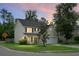 Charming two-story home featuring manicured lawn, attached garage and inviting curb appeal at dusk at 300 Greens Ct, Goose Creek, SC 29445