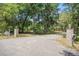 View of the entrance to the property from the paved road with brick columns and mature trees at 3002 Edenvale Rd, Johns Island, SC 29455