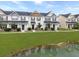 Exterior view of a row of modern townhomes with lush green lawns and a tranquil pond at 312 Silverdrop St, Goose Creek, SC 29445