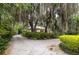 Inviting property featuring gravel drive and classic home obscured by lush greenery and mossy trees at 34 Formosa Dr, Charleston, SC 29407