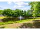 Picturesque pond with a fountain feature, surrounded by lush greenery and mature trees on a sunny day at 3413 Acorn Drop Ln, Johns Island, SC 29455