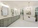 Bright bathroom featuring marble floors, gray vanity with double sinks, and a standalone tub at 4205 Cobble Trot Way, Johns Island, SC 29455