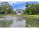 Scenic shot of a tranquil pond with fountain framed by lush trees, in front of a two-story home at 4205 Cobble Trot Way, Johns Island, SC 29455