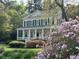 Traditional two-story home with black shutters, white porch, and colorful azaleas in the front yard at 4233 Lady Banks Ln, Ravenel, SC 29470