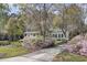 Two-story home with covered porch, flowering bushes, and lush landscaping along a paved driveway at 4233 Lady Banks Ln, Ravenel, SC 29470