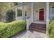 Charming front porch featuring brick steps, white railings, and a red front door with wreath at 4233 Lady Banks Ln, Ravenel, SC 29470