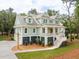 Stately light green two-story home with manicured front yard and a grand porch at 4291 Turtle Landing Ct, Johns Island, SC 29455