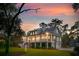 Charming two-story home with a spacious deck, lush landscaping, and serene sunset backdrop at 4291 Turtle Landing Ct, Johns Island, SC 29455