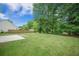 Wide backyard featuring a lush green lawn and mature trees, with a concrete patio slab at 5406 Woodbreeze Dr, North Charleston, SC 29420