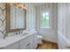 Stylish powder room with decorative wallpaper, elegant vanity with marble top, and modern fixtures at 5625 Crystal Harbor Ln, Hollywood, SC 29449