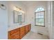 Bright bathroom has an arched window, marble countertop vanity with wood cabinets, and decorative light fixture at 5625 Crystal Harbor Ln, Hollywood, SC 29449