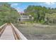 Beautiful two-story traditional home with a red roof is surrounded by lush landscaping, oak trees, and native marsh grasses at 5625 Crystal Harbor Ln, Hollywood, SC 29449