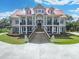 Beautiful traditional home with a red roof, grand staircase, and lion statues stands out against the blue sky and lush landscaping at 5625 Crystal Harbor Ln, Hollywood, SC 29449